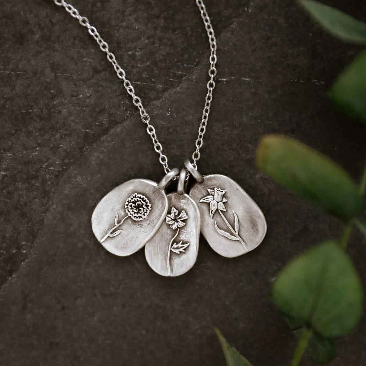 pewter Birth Flower necklace charms on beige background