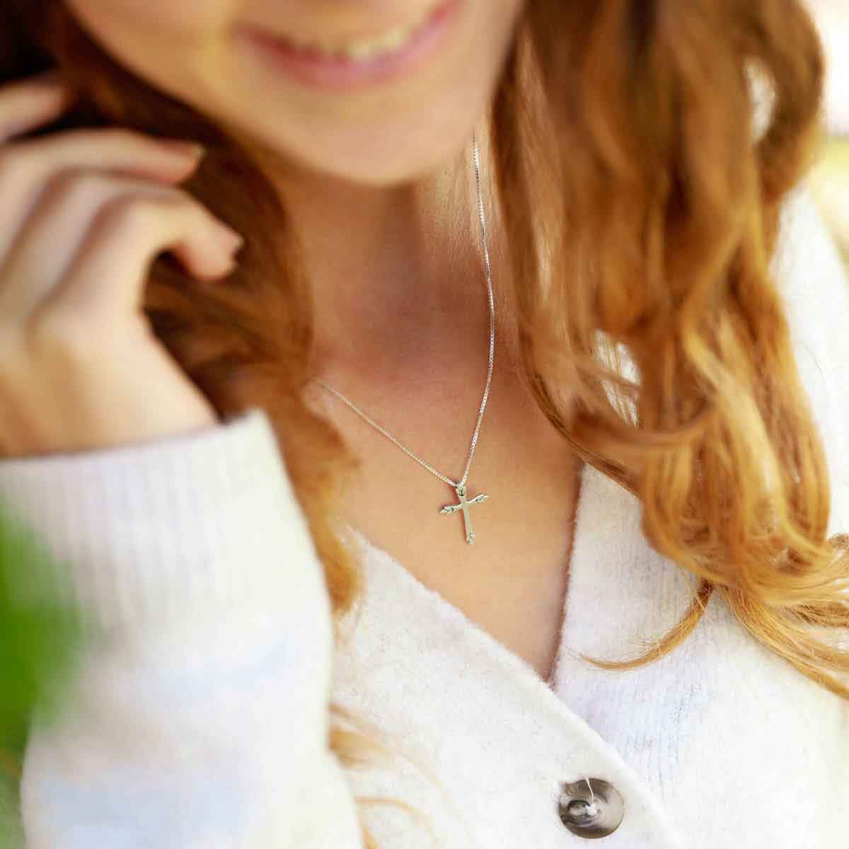 woman holding a sterling silver Blooming Love Cross necklace