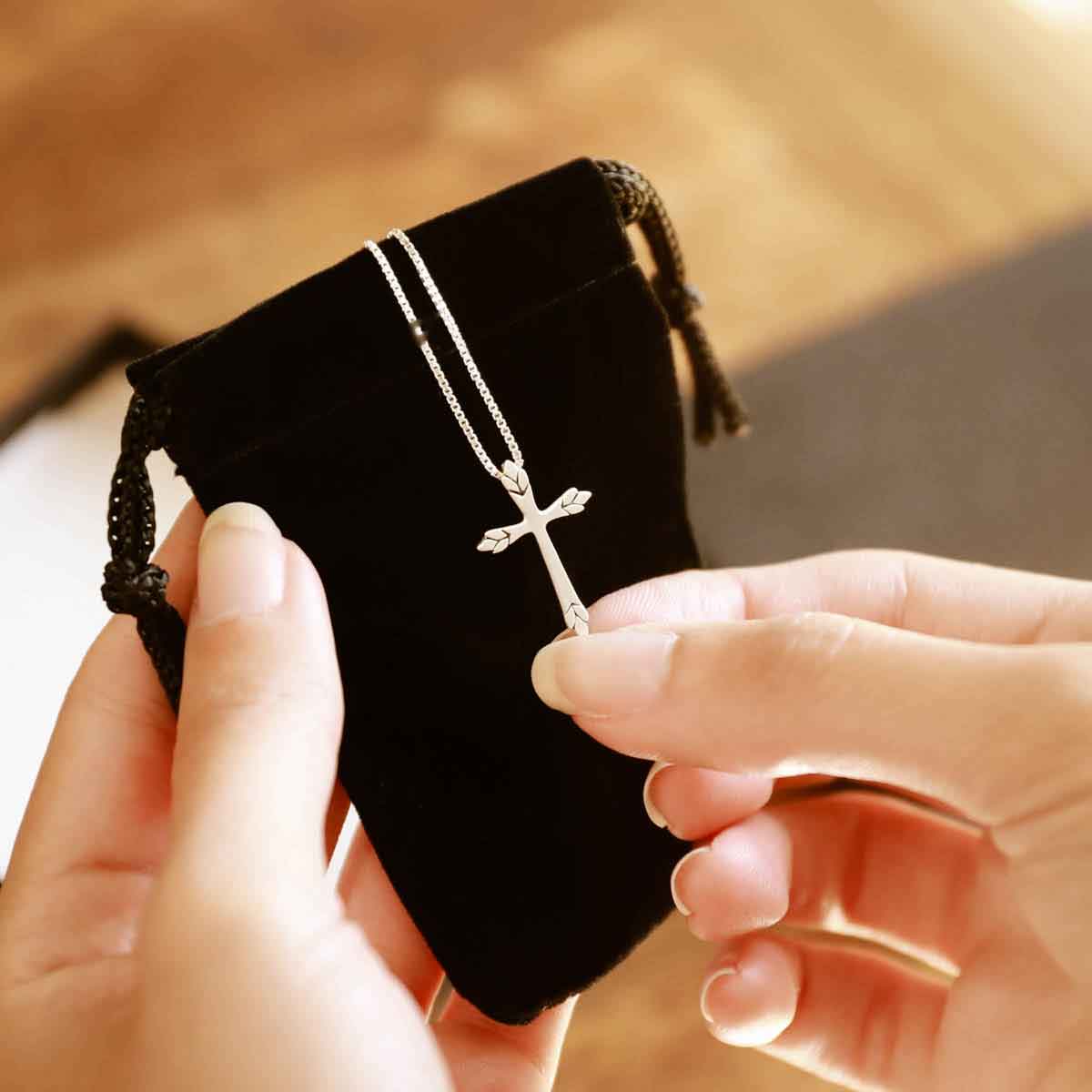 woman holding a sterling silver Blooming Love Cross necklace