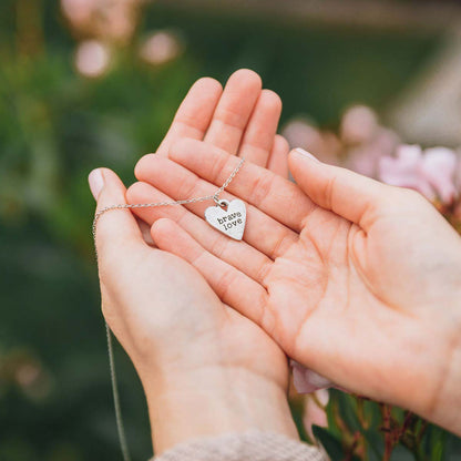 Girl holding her Brave Love heart necklace handcrafted in pewter with choice of color epoxy