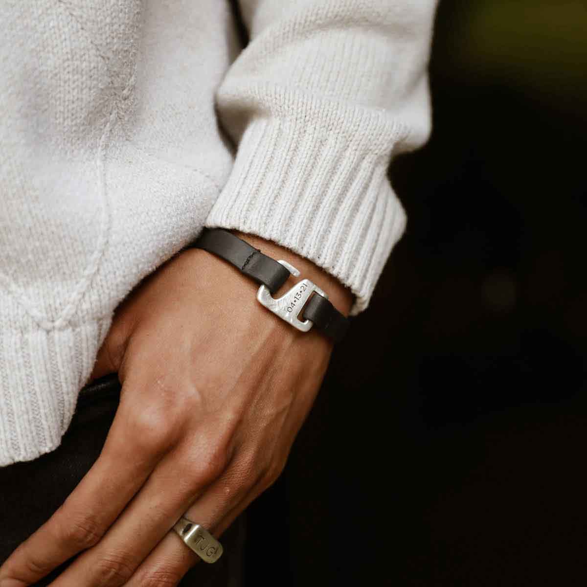 Man wearing Black Connection bracelet handcrafted with a distressed black leather strap and a sterling silver closure customizable with a name