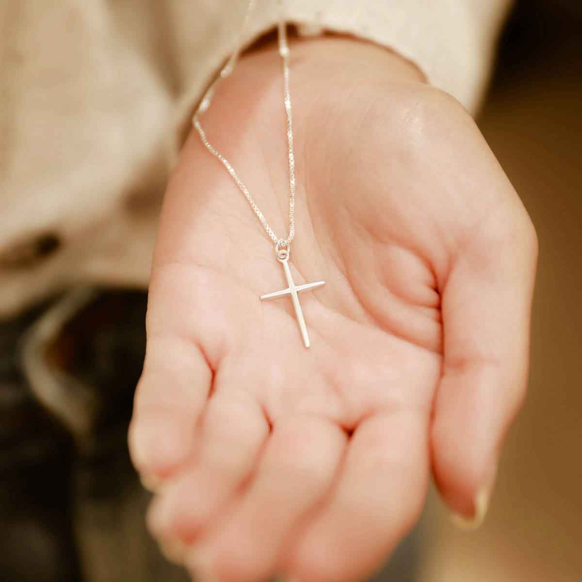 woman wearing and holding a sterling silver Covenant of Love Cross necklace