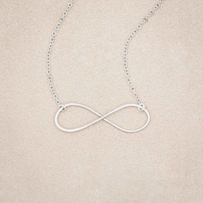 A sterling silver Forever, For Always Infinity Necklace, on beige background