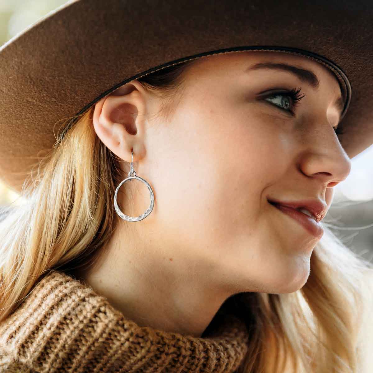 pewter Hammered Hoop earrings dangling from a white vase
