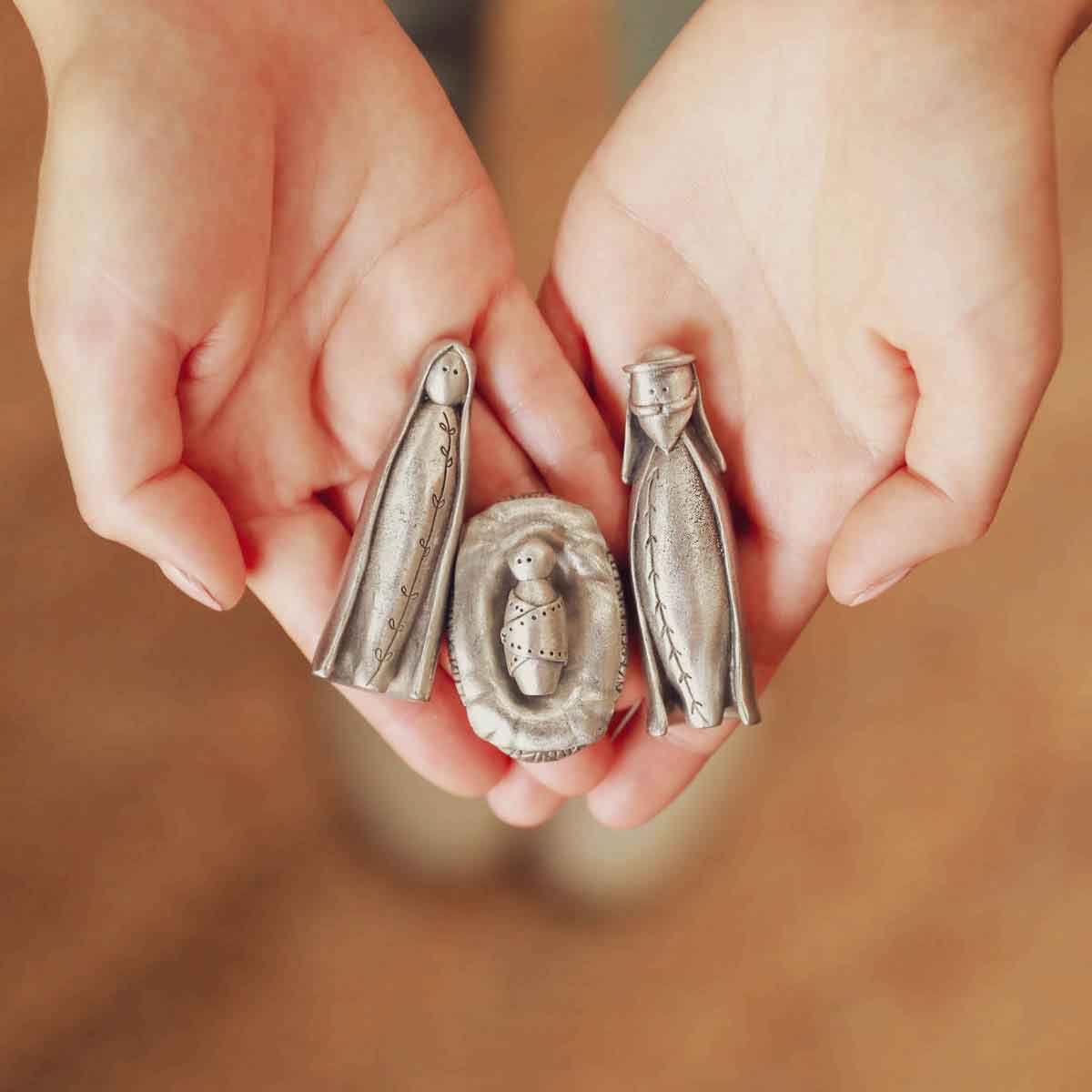 hands holding the pewter holy family nativity figurine set