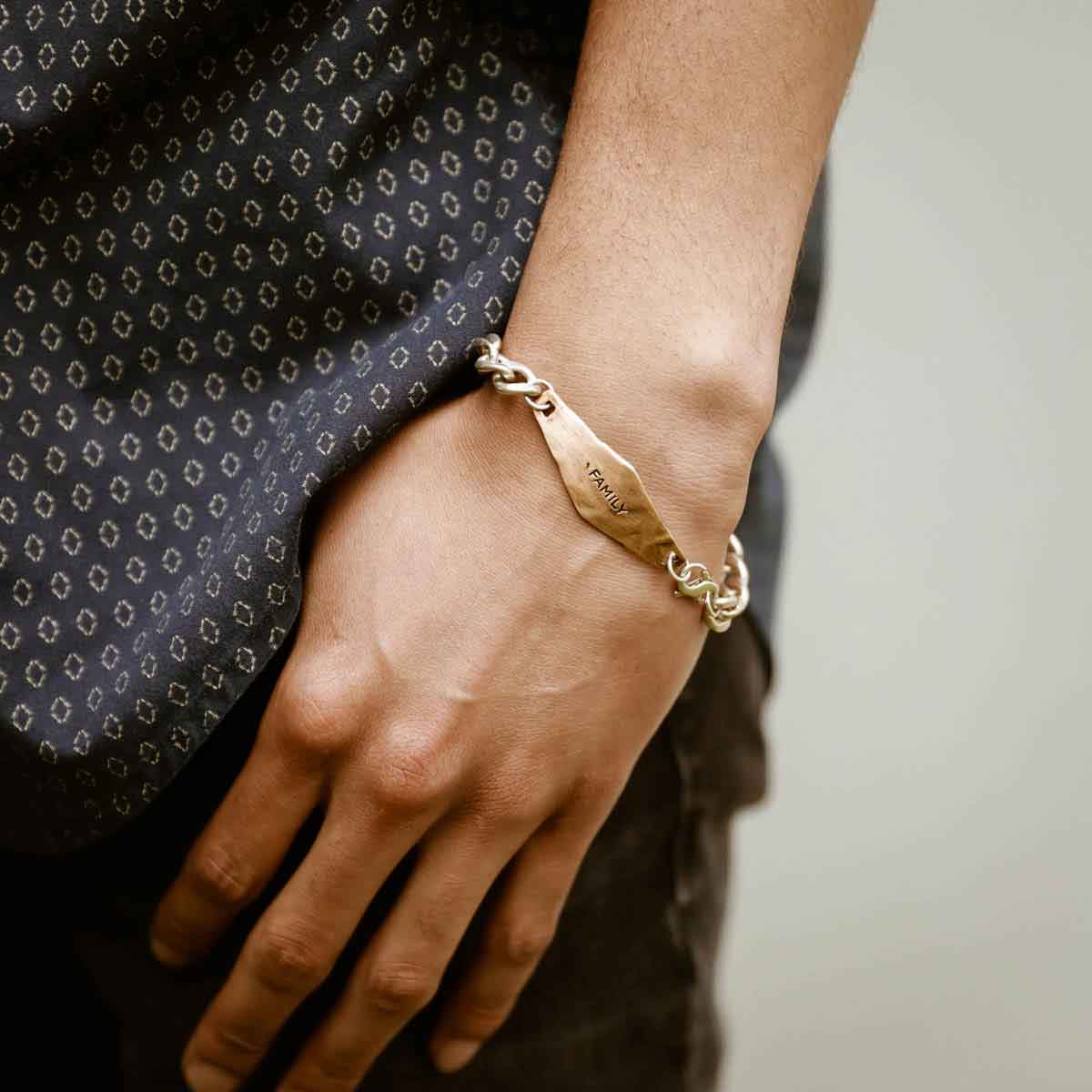 man holding the Identity Bracelet with a personalized Bronze metal plate and Sterling Silver chain