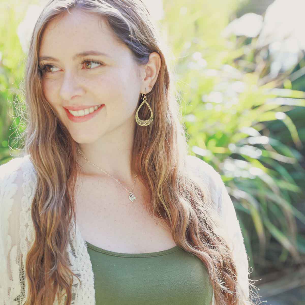 Girl wearing her Light + Bright hearts necklace handcrafted in sterling silver with a matte brushed finish and the heart charm hung next to a vintage freshwater pearl