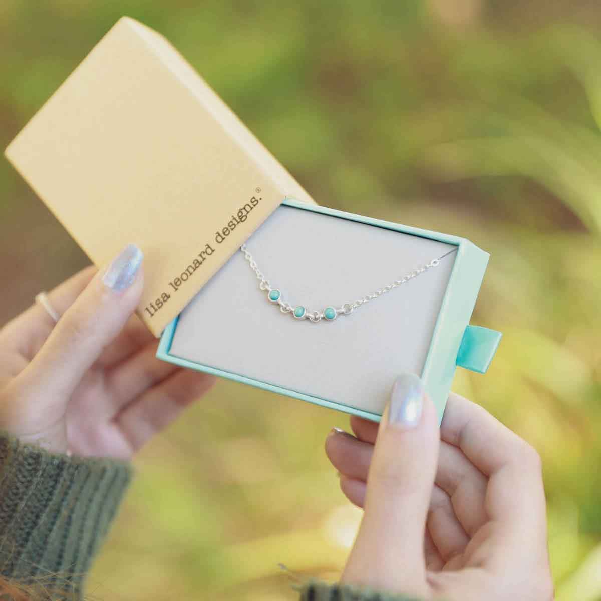 girl holding a sterling silver Lighthearted Turquoise Bracelet in a lisa leonard box