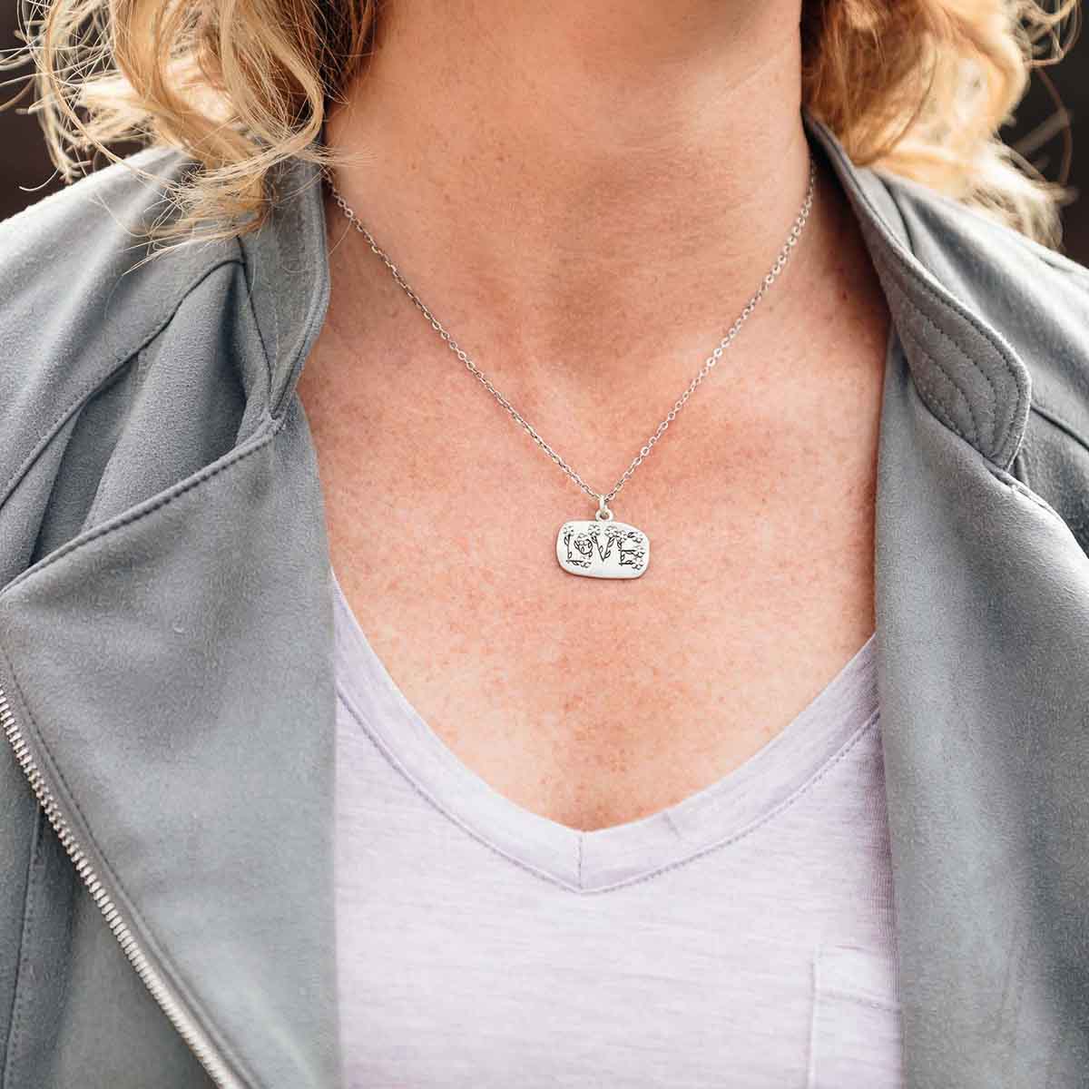 Woman wearing her Love and Wildflowers necklace handcrafted in sterling silver including charm with a matte brushed finish