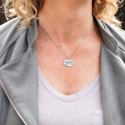 Woman wearing her Love and Wildflowers necklace handcrafted in sterling silver including charm with a matte brushed finish