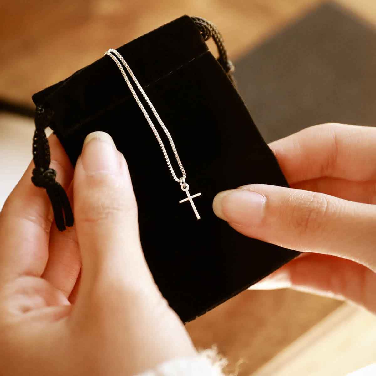 woman holding a sterling silver Love & Accepted Cross necklace