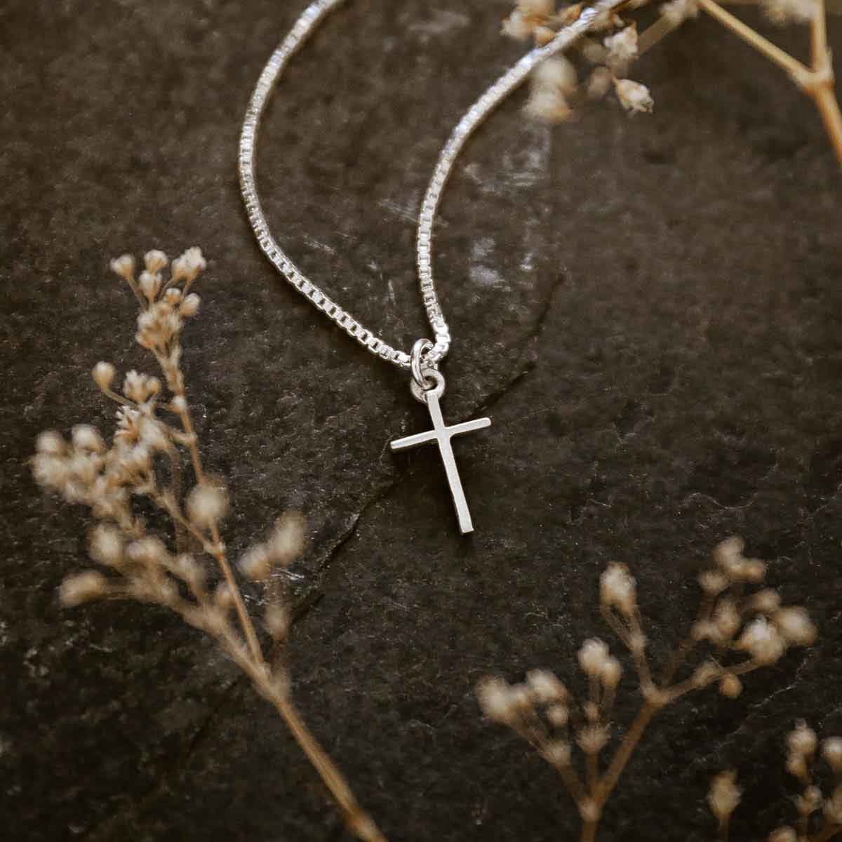 woman holding a sterling silver Love & Accepted Cross necklace