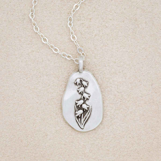 sterling silver May Birth flower necklace, on beige background