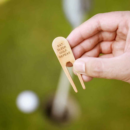 hand holding bronze personalized divot tool on a golf course
