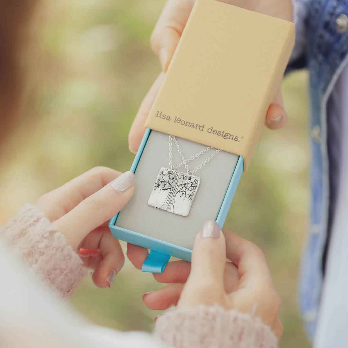 hands holding a sterling silver rooted in love necklace set
