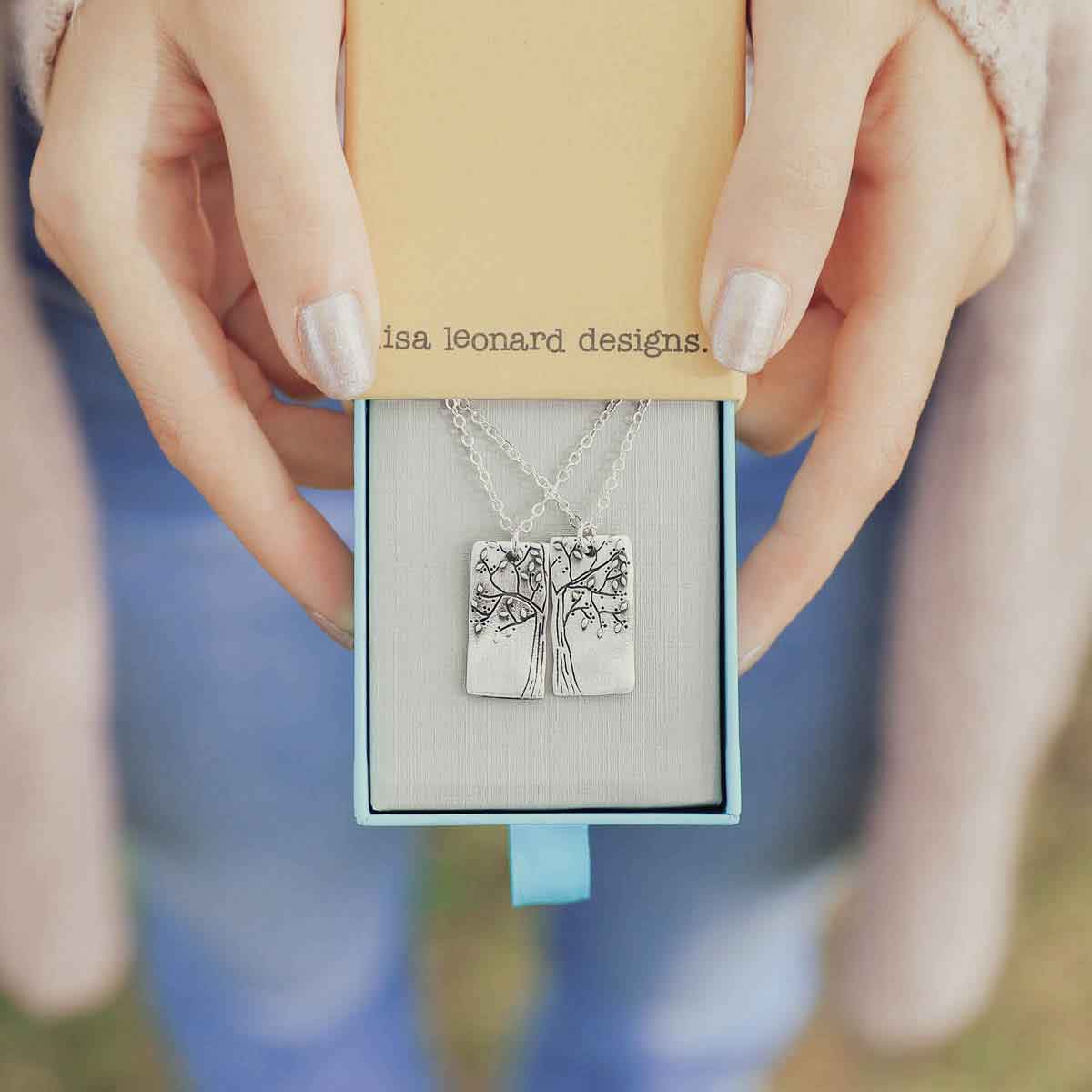 girl giving the sterling silver rooted in love necklace set in a lisa leonard necklace box