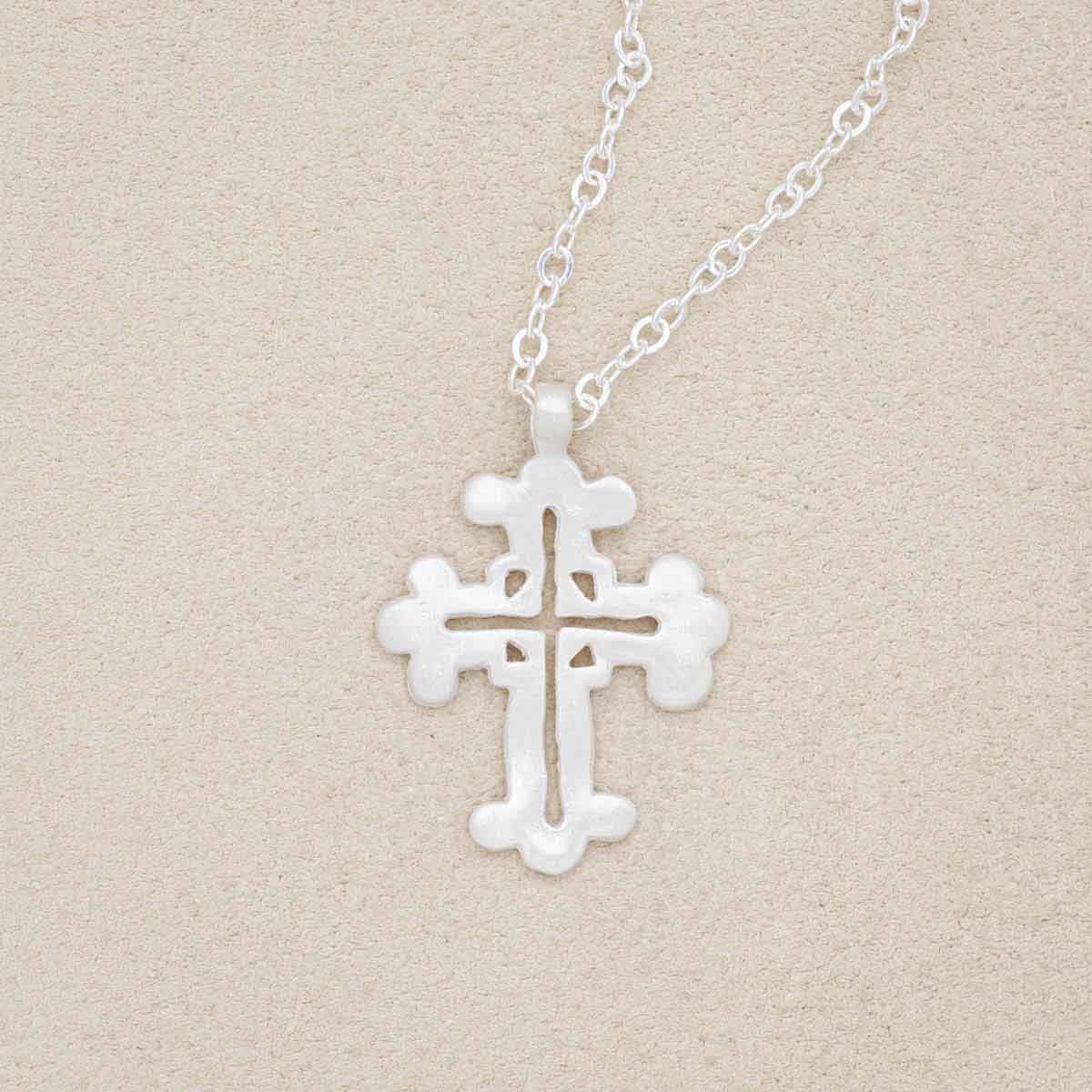 sterling silver work of art cross necklace on beige background